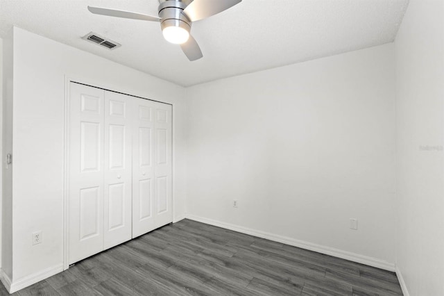 unfurnished bedroom featuring a closet, ceiling fan, a textured ceiling, and dark hardwood / wood-style floors