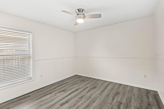 empty room with ceiling fan, wood-type flooring, and a textured ceiling