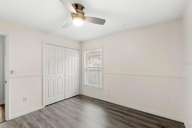 unfurnished bedroom with a closet, a textured ceiling, light hardwood / wood-style floors, and ceiling fan