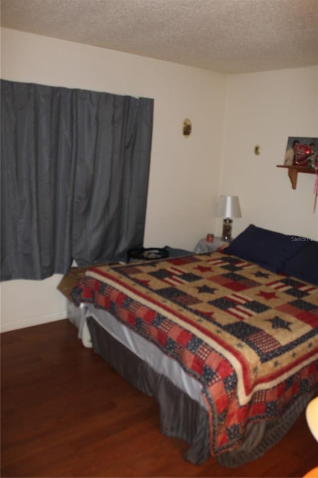 bedroom with a textured ceiling and dark hardwood / wood-style flooring