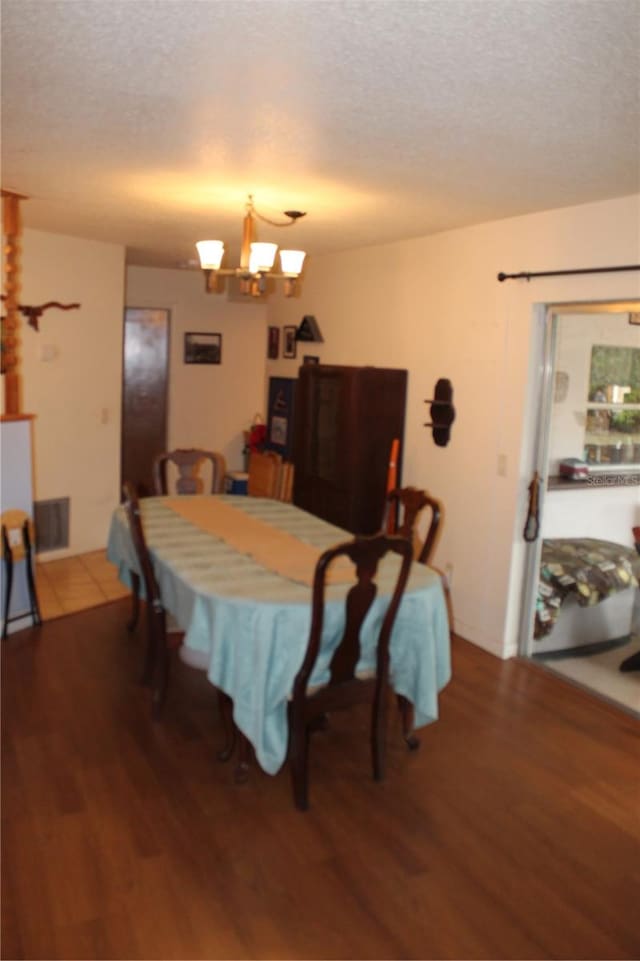 dining room with a notable chandelier, hardwood / wood-style flooring, and a textured ceiling