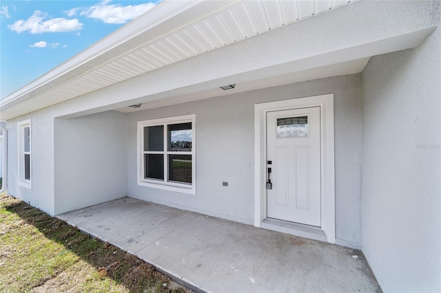 view of exterior entry featuring a patio area and stucco siding