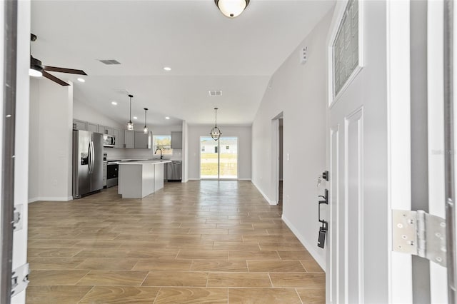 interior space featuring a kitchen island, open floor plan, light countertops, appliances with stainless steel finishes, and gray cabinets