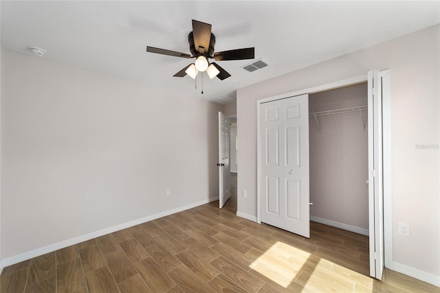 unfurnished bedroom featuring a ceiling fan, visible vents, baseboards, and wood finished floors