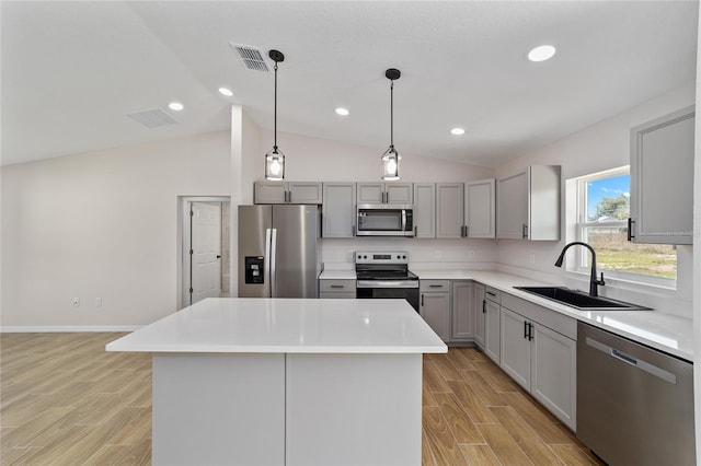 kitchen with appliances with stainless steel finishes, light countertops, a sink, and a center island