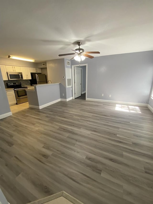 unfurnished living room featuring ceiling fan and dark hardwood / wood-style floors