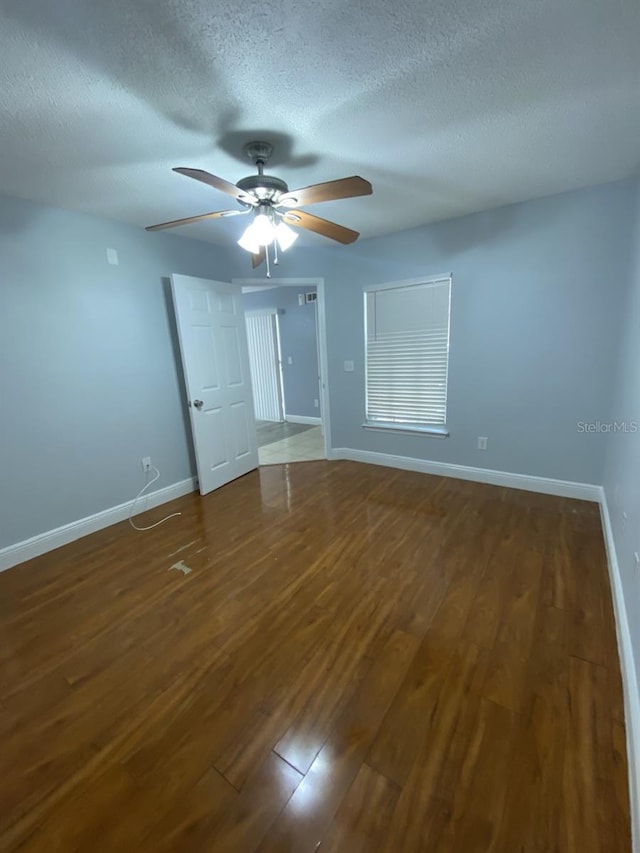 spare room with dark hardwood / wood-style floors, a textured ceiling, and ceiling fan