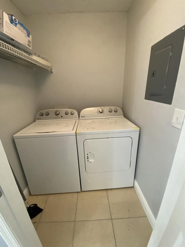 clothes washing area featuring light tile patterned floors, electric panel, and separate washer and dryer