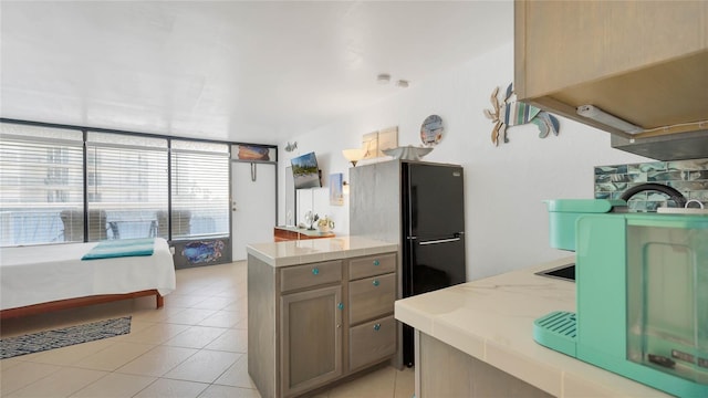 kitchen with black refrigerator, light tile patterned flooring, and plenty of natural light