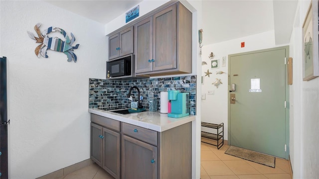 kitchen with tasteful backsplash, dark brown cabinetry, sink, and light tile patterned flooring