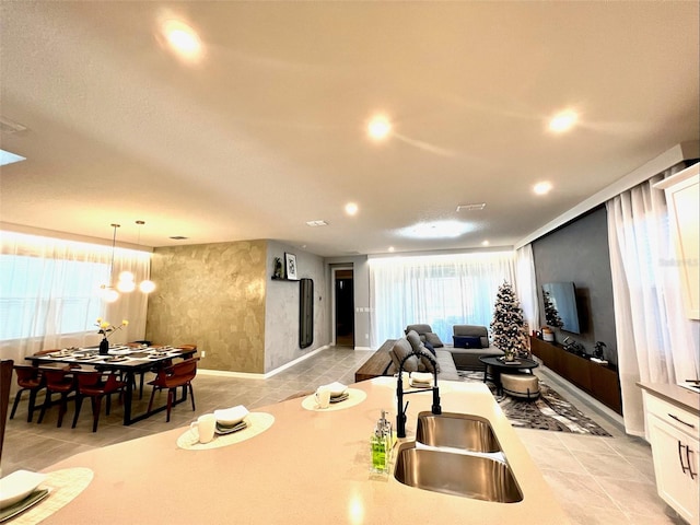 kitchen with white cabinets, hanging light fixtures, light tile patterned floors, a chandelier, and sink