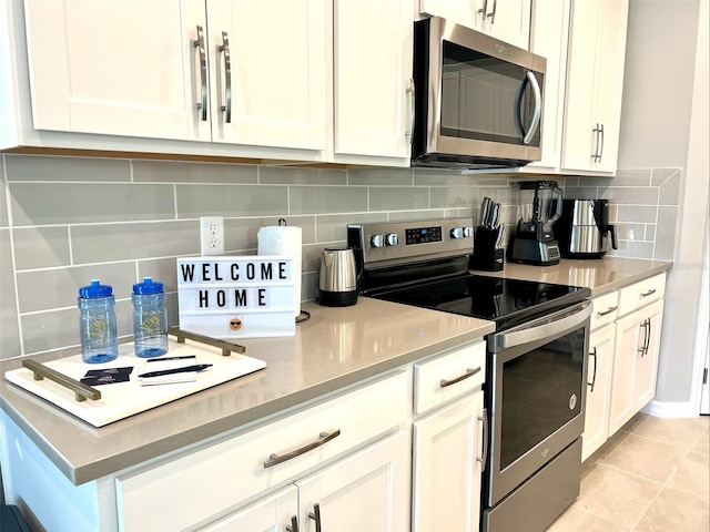 kitchen with white cabinets, stainless steel appliances, backsplash, and light tile patterned floors