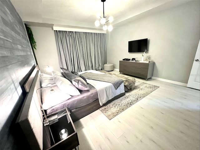 bedroom with light hardwood / wood-style flooring and a notable chandelier