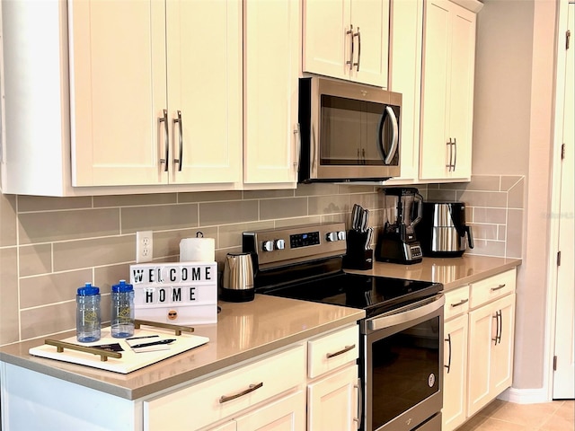 kitchen with backsplash, stainless steel appliances, light tile patterned flooring, and white cabinets