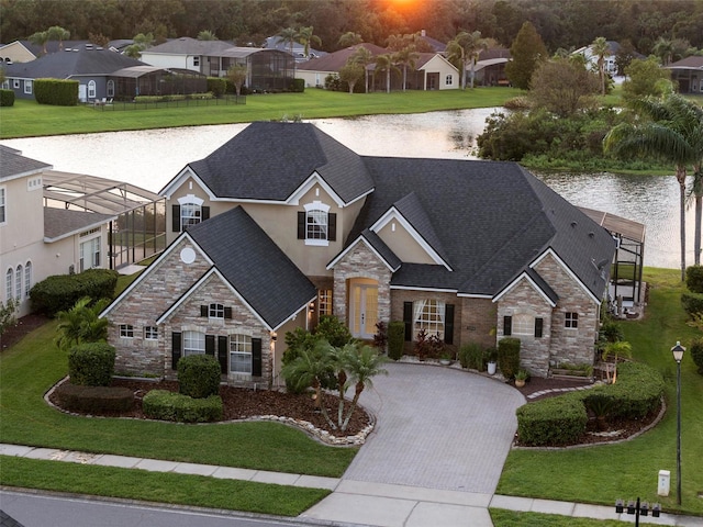 craftsman-style house featuring glass enclosure, a water view, and a front lawn