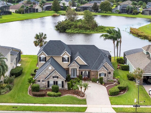 view of front facade featuring glass enclosure, a water view, and a front lawn