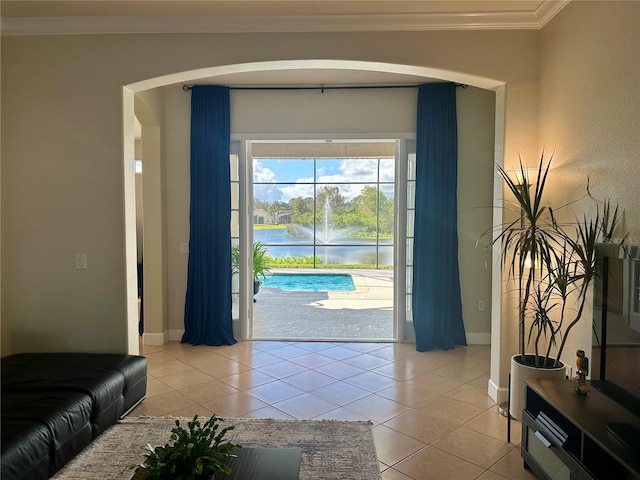 doorway featuring a water view, light tile patterned floors, and crown molding