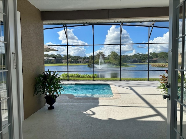 view of pool with a water view, glass enclosure, and a patio