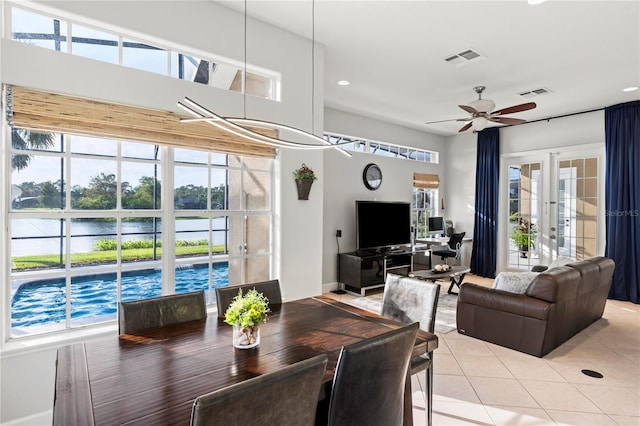 dining room with french doors, a water view, light tile patterned floors, and ceiling fan