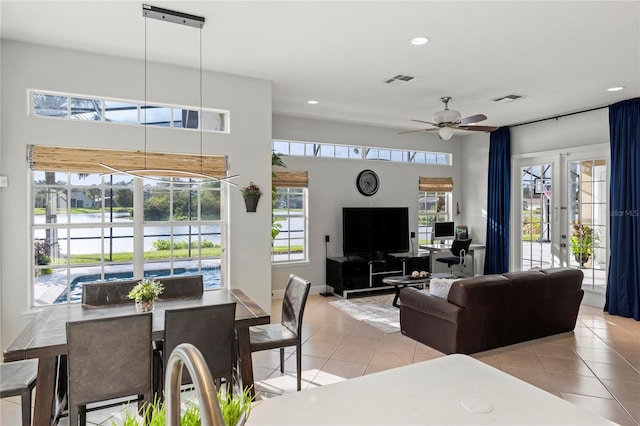 tiled dining area featuring ceiling fan, a water view, and a healthy amount of sunlight