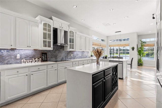 kitchen with white cabinets, decorative backsplash, wall chimney exhaust hood, and a kitchen island