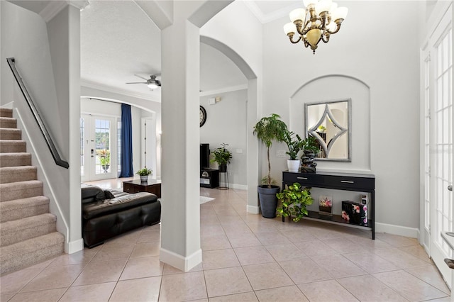 tiled foyer featuring ceiling fan with notable chandelier and crown molding