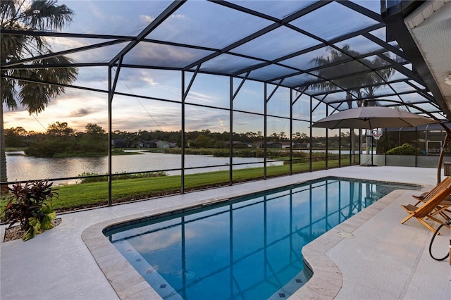 pool at dusk featuring a lanai, a water view, and a patio area