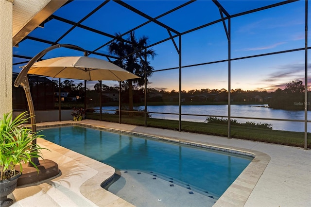 pool at dusk with a patio, glass enclosure, and a water view