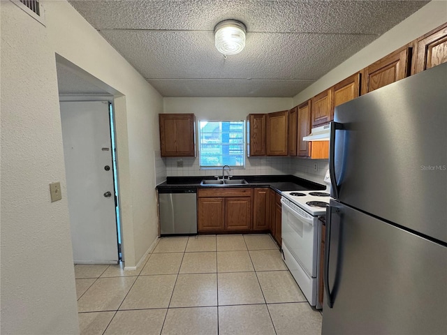 kitchen with backsplash, appliances with stainless steel finishes, sink, and light tile patterned floors