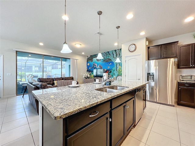 kitchen with dark brown cabinets, a center island with sink, sink, decorative light fixtures, and appliances with stainless steel finishes