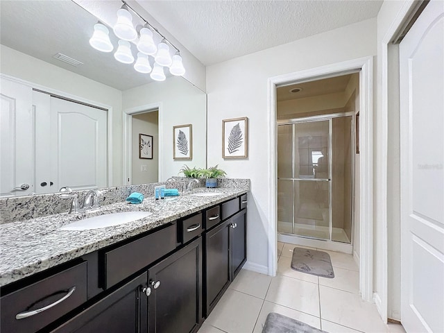 bathroom with vanity, a textured ceiling, tile patterned flooring, and a shower with door