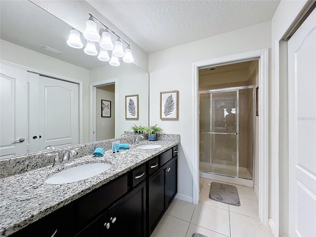 bathroom featuring vanity, tile patterned flooring, a textured ceiling, and an enclosed shower