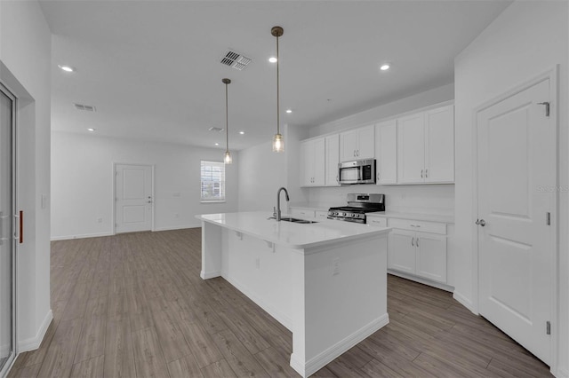 kitchen with pendant lighting, an island with sink, white cabinetry, sink, and stainless steel appliances