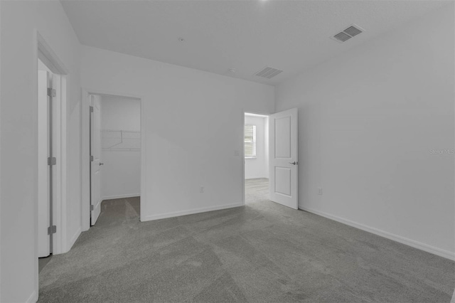 unfurnished bedroom featuring light colored carpet, a spacious closet, and a closet