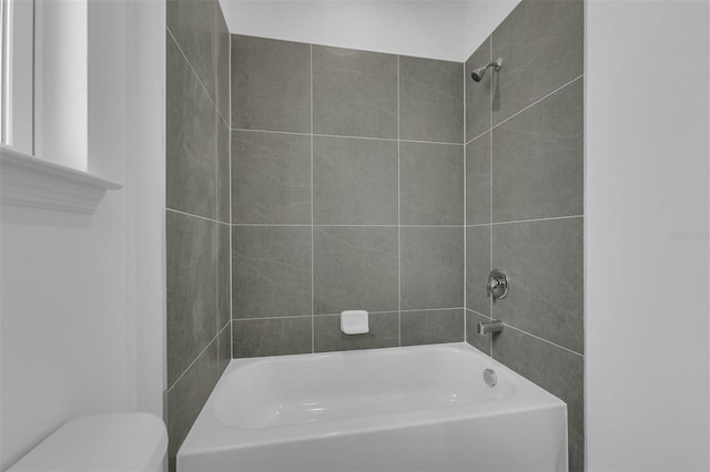 bathroom featuring toilet and tiled shower / bath combo