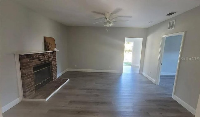 unfurnished living room with ceiling fan, a brick fireplace, and dark hardwood / wood-style floors