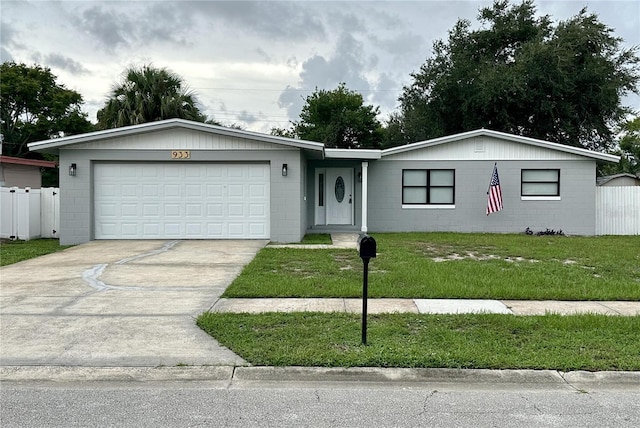 single story home with fence, a front lawn, concrete driveway, concrete block siding, and a garage