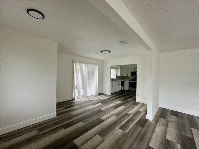 unfurnished living room featuring dark wood-style floors, baseboards, a sink, and visible vents