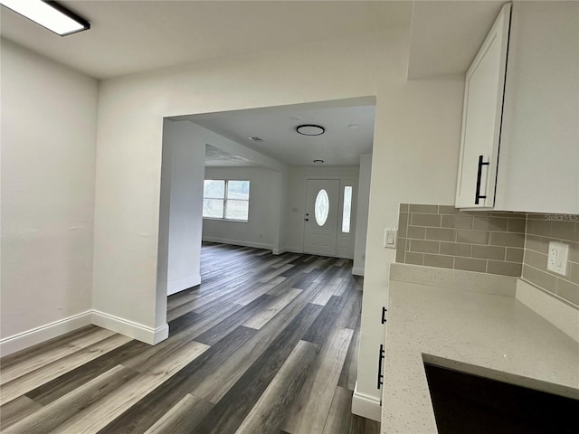 kitchen featuring white cabinets, dark wood-style flooring, and light stone countertops