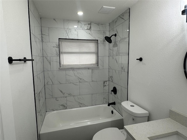 full bathroom featuring vanity, tiled shower / bath, and toilet