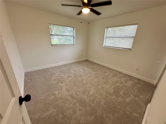 carpeted spare room with a ceiling fan and baseboards