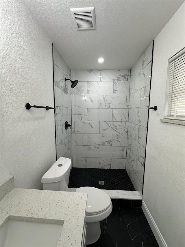 bathroom featuring vanity, tiled shower, a textured ceiling, and toilet