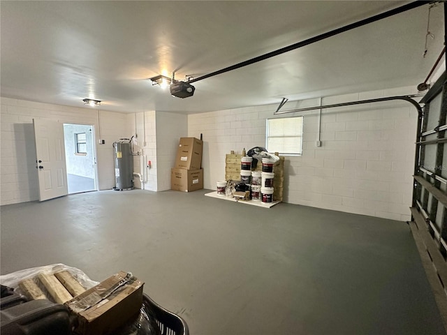 garage with a garage door opener, electric water heater, and concrete block wall