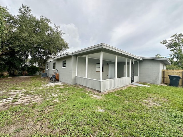 back of property with central air condition unit, a lawn, and a sunroom