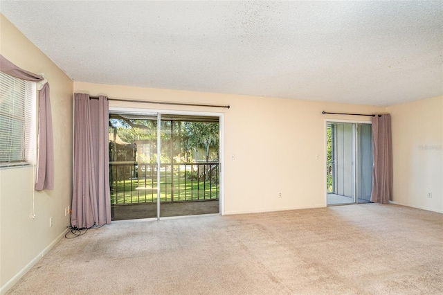 empty room with a textured ceiling and light colored carpet