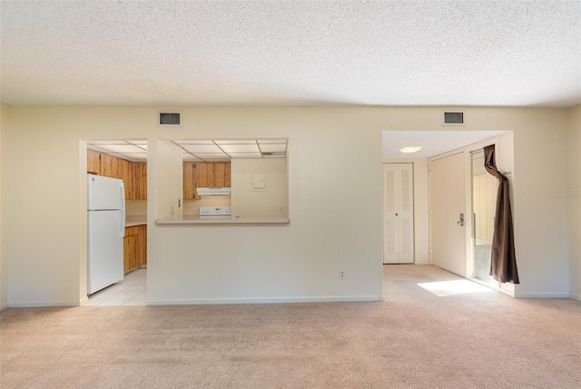 unfurnished living room with a textured ceiling and light colored carpet