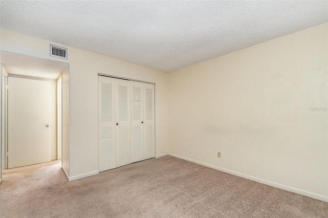 unfurnished bedroom with light carpet, a closet, and a textured ceiling