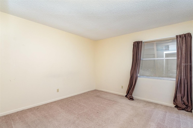 unfurnished room featuring a textured ceiling and light carpet