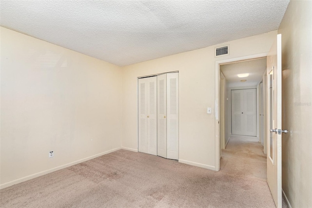 unfurnished bedroom featuring a closet, a textured ceiling, and light carpet