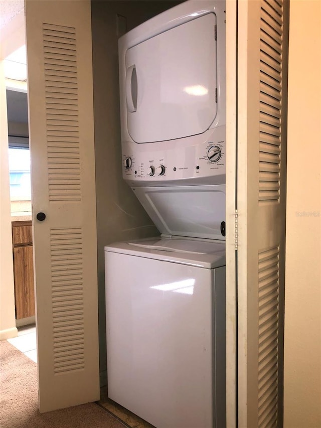 laundry area featuring light colored carpet and stacked washer / drying machine